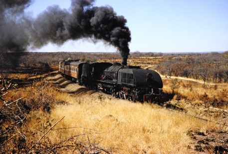 National Railways of Zimbabwe Garratt steam locomotive no. 417 moves a passenger train with ease through the grassy landscape in Bulawayo, Zimbabwe, on August 4, 1991. Photograph by Fred M. Springer, © 2014, Center for Railroad Photography and Art. Springer-Hedjaz-ZimZam(1)-21-07