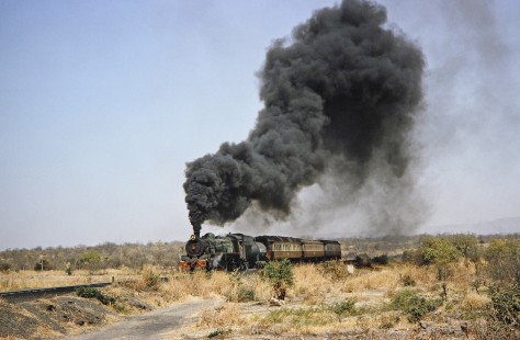 National Railways of Zimbabwe steam locomotive no. 6 under a large cloud of smoke as it carries a short passenger train down the track in Hwange, Matabeleland, Zimbabwe, on August 6, 1991. Photograph by Fred M. Springer, © 2014, Center for Railroad Photography and Art. Springer-Hedjaz-ZimZam(1)-24-03