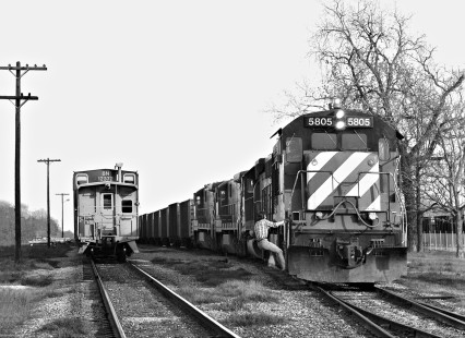 A Missouri–Kansas–Texas Railroad crewman climbs aboard a train of coal empties at the yard in Smithville, Texas, as an inbound train waits for a new crew in January 1981. Wyoming coal traffic spread Burlington Northern Railroad power and cabooses over much of the central U.S. Photograph by J. Parker Lamb, © 2016, Center for Railroad Photography and Art. Lamb-02-046-10