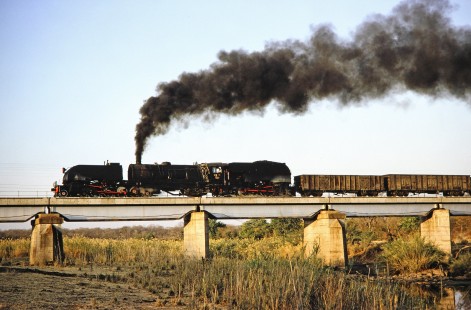 National Railways of Zimbabwe steam locomotive crosses a bridge in Matetsi, Zimbabwe on August 6, 1991. Photograph by Fred M. Springer, © 2014, Center for Railroad Photography and Art. Springer-ZimZam(2)-Swiss-19-25