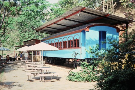 A blue Estrada de Ferro Campos do Jordao passenger car sits next to a nearby food stand and dining area in Kingdom of Clearwater, Sao Paulo, Brazil, on November 2, 1990. Photograph by Fred M. Springer, © 2014, Center for Railroad Photography and Art. Springer-PA-BR-SOAM-ME-ARG2-10-38