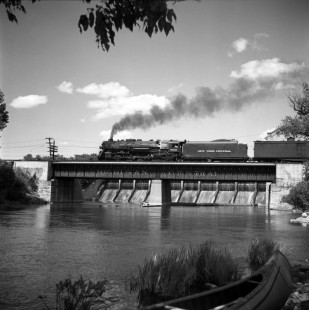 A westbound New York Central (NYC) passenger train crosses a bridge over the Huron River in Ann Arbor, Michigan, circa 1950. The Barton Dam is visible behind the bridge. Photograph by Robert A. Hadley. © 2016, Center for Railroad Photography and Art