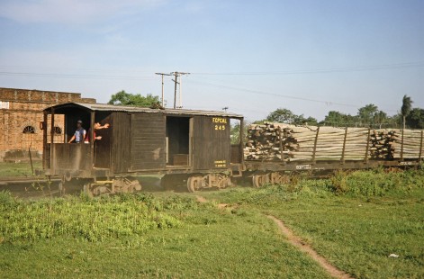 Workers wave from Ferrocarril Presidente Carlos Antonio López (later Ferrocarriles del Paraguay SA FEPASA) caboose no. 245 as it rolls behind freight cars full of logs in Ypacaraí, Central, Paraguay, on October 22, 1991. Photograph by Fred M. Springer, © 2014, Center for Railroad Photography and Art. Springer-ARG-PA-CHI-BO2-06-12