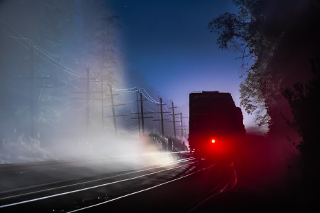 Norfolk Southern freight train 15T has taken the siding at Shenandoah Junction, West Virginia, and its end-of-train device flashes into the night of September 27, 2014. On the adjacent track, intermodal train 214 resumes its trek north, illuminating the right-of-way with its headlights through the drifting midnight fog.

Read more about the <a href="http://www.railphoto-art.org/awards/2017-awards/" rel="nofollow">2017 John E. Gruber Creative Photography Awards Program</a>.