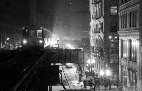 During an evening snow storm in Chicago, the pickup shoes of an L train arc into the night, momentarily lighting the dark building canyon facades.

Read more about the <a href="http://www.railphoto-art.org/awards/2017-awards/" rel="nofollow">2017 John E. Gruber Creative Photography Awards Program</a>.