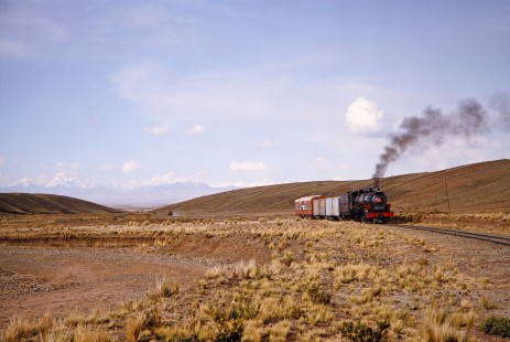 Snow-capped mountains and the plateau landscape surround the Empresa Nacional de Ferrocarriles Bolivia 2-10-2 steam locomotive no. 704 as it progresses to Capiri, Western Bolivia, Bolivia, on September 30, 1992. Photograph by Fred M. Springer, © 2014, Center for Railroad Photography and Art. Springer-ARG-PA-CHI-BO2-13-04