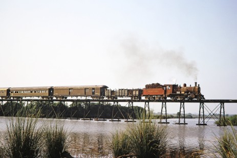 Ferrocarril Presidente Carlos Antonio López (later Ferrocarriles del Paraguay SA FEPASA) steam locomotive no. 59 crosses over a bridge in Encarnación, Itapúa, Paraguay, on October 21, 1991. Photograph by Fred M. Springer, © 2014, Center for Railroad Photography and Art. Springer-ARG-PA-CHI-BO2-04-29