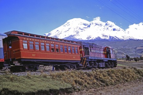 Empresa de Ferrocarriles Ecuatorianos diesel locomotive no. 164 and its passenger train near the high peaked and inactive stratavolcano "Chimborazo" in Riobamba, Chimborazo, Ecuador on July 27, 1988. Photograph by Fred M. Springer, © 2014, Center for Railroad Photography and Art, Springer-ECU1-12-21
