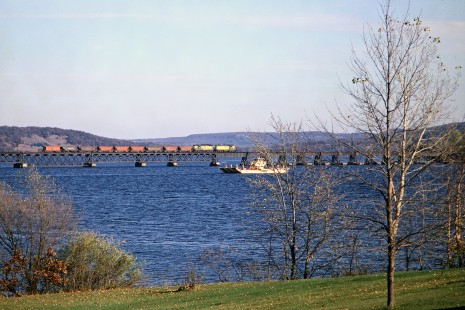 Chicago and North Western Railway freight train crossing the Wisconsin River at Merrimac, Wisconsin, as a ferry passes on Saturday, October 26, 1968. The ferry is a free service on State Highway 113; the train is likely hauling cars loaded with ballast from the quarry at Rock Springs. Photograph by Thomas F. McIlwraith, McIlwraith-01-024-20, © 2018, Center for Railroad Photography & Art, <a href="http://www.railphoto-art.org" rel="noreferrer nofollow">www.railphoto-art.org</a>