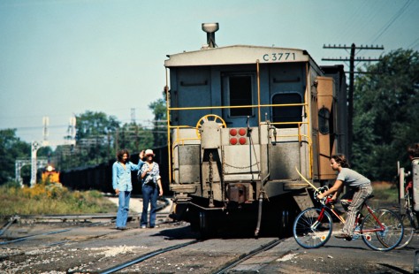 Baltimore and Ohio Railroad freight train passes on Chesapeake and Ohio track as anxious pedestrians and cyclists cross in Fostoria, on September 11, 1976. Photograph by John F. Bjorklund, © 2016, Center for Railroad Photography and Art. Bjorklund-92-23-21