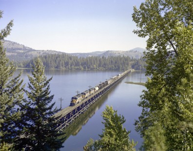 Milwaukee Road diesel locomotive no. 18 crosses Benewah Lake near Ramsdell, Idaho, with westbound freight train no. 201 on September 13, 1979. Photograph by Victor Hand. Hand-MILW-C67-16