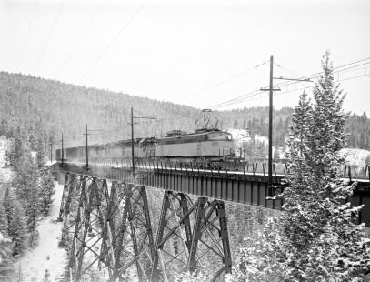 Milwaukee Road electric locomotive no. E75 with eastbound freight crosses the Continental Divide at Pipestone Pass (15 miles south of Butte, Montana) on December 6, 1972. 1972- Photograph by Victor Hand. Hand-MILW-67-025
