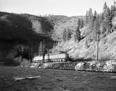 Milwaukee Road electric locomotive no. E21 hauls westbound freight along the Saint Regis River near Henderson, Montana, on May 16, 1974. Photograph by Victor Hand. Hand-MILW-67-046