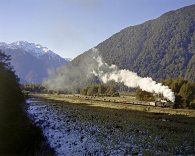 New Zealand Government Railways steam locomotive no. 1209 leads eastbound freight train between Greymouth and Otira, New Zealand on July 25, 1966 near Aickens, New Zealand, on July 25, 1966. Photograph by Victor Hand. Hand-NZGR-C10-35