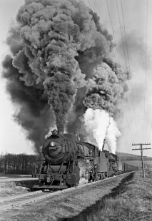 Lehigh and New England steam locomotives 307 and 401 struggle east with twenty-three cars on the steep grade between Bath and Summit, Pennsylvania, on March 10, 1946. They are "doubling the hill" with the first half of a forty-seven car train. Note the white plumes of steam from the booster engines operating on each of the tenders. Photograph by Donald W. Furler, Furler-02-054-01, © 2017, Center for Railroad Photography and Art