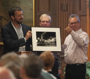 Jeff Mast, right, won the Friday raffle for a silver gelatin print by Jim Shaughnessy, presented by Scott Lothes and Norm Carlson