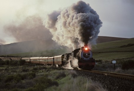 South African Railways class 19C steam locomotive nos. 1882 and 2439 lead a passenger train near Mission, Transvaal (present-day Limpopo), South Africa, May 26, 1993. Photograph by Katherine Botkin. BOTKINK-113-KT-329,© 1993, Katherine Botkin.