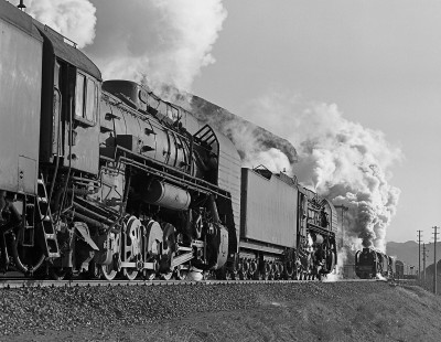 Jitong Railway QJ-class steam locomotive nos. 6828 and 7143 lead eastbound train in foreground of image while westbound train approaching is led by Jitong Railway QJ-class nos. 6110 and 6851. Image shot at Galadesitai Station in Inner Mongolia, China, on November 15, 2002. Photograph by William Botkin. © 2002, William Botkin