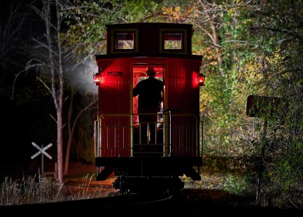 The conductor minds his narrow gauge caboose as the Locust Heights & Western Railroad Climax steam locomotive powered logging train leaves Clarksburg, West Virginia, early in the morning, on October 26, 2019. © Matthew Malkiewicz