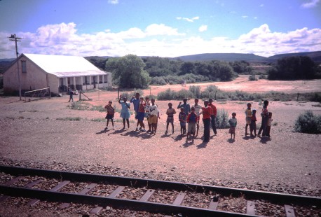 A group of children gather to wave at a passenger train pulled by South African Railway (SAR) steam locomotive no. 1882 as it travels through Oudtshoorn, Western Cape, South Africa, on March 24, 1995. Photograph by Fred Springer. © 2020, Center for Railroad Photography and Art, Springer-So.Africa(1)-17-01