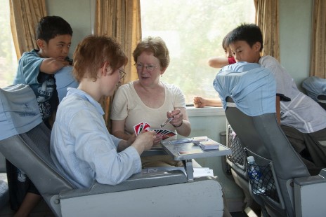 On a humid spring afternoon in southern Vietnam, boys aboard train SE6 closely observe a game of Uno between Americans Maureen Muldoon and her mother, Lyn Corder. © Scott Lothes