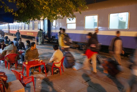 In predawn darkness at Hanoi, Vietnam, passengers disembarking from train SE2 pass diners eating breakfast at the station, on April 9, 2007.