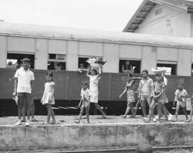 Curious children gather on a station platform in Bindjei, Sumatra, Indonesia, on September 10, 1971. They walk along a mixed train traveling to Medan, and led by Perusahaan Negara Kereta Api (PNKA) steam locomotive no. 62. Photograph by Victor Hand, Hand-PNKA-22-061