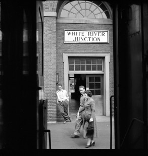A view looking out from a passenger rail car as a couple strolls the rail platform at White River Junction, Vermont, on August 23, 1953. Photograph by Wallace Abbey. © 2020, Center for Railroad Photography and Art, Abbey-02-021-06