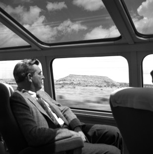 A man gazes out a window of an Atchison, Topeka & Santa Fe Railroad (AT&SF) passenger car at the passing landscape, on April 20, 1953. Photograph by Wallace Abbey. © 2020, Center for Railroad Photography and Art, Abbey-01-100-03