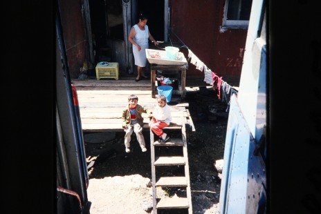 A Ferrocarriles Nacionales de Mexico (N de M) passenger train passes through a village in Mexico, allowing the photographer to spot two siblings playing on their front porch, just feet away from the tracks, on March 17, 1993. Photograph by Fred Springer. © 2020, Center for Railroad Photography and Art, Springer-Mexico-Australia-06-07