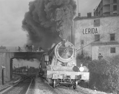 Onlookers from a small traffic bridge are cloaked in smoke as Renfe Operadora (RENFE) steam locomotive no. 242-0286 sets off from Lerida, Spain en route from Barcelona to Barbastro, on May 28, 1968. Photograph by Victor Hand, Hand-RENFE-15-063