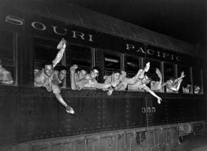 "U.S. railroads engage in all-out war effort, between 1941 and 1945." Photograph shows several men waving from the open windows of a troop train car leaving a Midwestern United States military camp. Library of Congress Prints and Photographs Division, LC-USZ62-133816