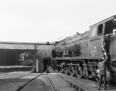 Renfe Operadora (RENFE) steam locomotive no. 241-2210 pauses on a turntable in a roundhouse in Zaragoza, Spain, on May 29, 1968. In prepping the engine, a shop worker passes a bucket of water up to the engine crew. Photograph by Victor Hand, Hand-RENFE-15-074