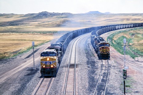Union Pacific Railroad no. 5959 southbound loaded coal run heads toward Bill an unincorporated community in Converse county Wyoming terminal, passing Burlington Northern Santa Fe Railway loads waiting for green signal, August 2005. Photograph by J. Parker Lamb. Lamb-03-041-15.JPG; © 2016, Center for Railroad Photography and Art