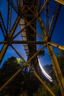 Night has fallen and stars shine brightly from above as train U81 grinds upgrade across the trestle at Slab Fork, West Virginia, on the former Virginian Railway's Deepwater Line on July 20, 2016. The Virginian spared no expense when it built this railroad and the frame work detailed in this shot showcases that. The train is en route to Alloy Yard from Elmore Yard in Mullens, West Virginia.

Read more about the 2020 John E. Gruber Creative Photography Awards Program: <a href="http://www.railphoto-art.org/connections-2020/" rel="noreferrer nofollow">www.railphoto-art.org/connections-2020/</a>
