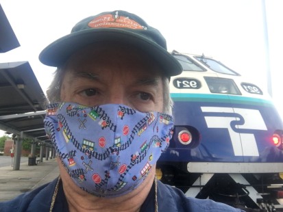 Bob Alkire with his face mask, in front of a Sounder commuter train at Everett, Washington.

On June 18, Bob Alkire of Everett, Washington “decided it was time for some train riding.” Boarding a bus, Alkire rode a half hour to downtown Seattle, and then caught one of Sound Transit’s commuter trains back north to his hometown. “We made the usual stops in Edmonds and Mukilteo before arriving back at the Everett Transit Center. About ten minutes after our arrival, the Empire Builder pulled into the station on its way to Chicago. Surprise, Surprise, a passenger actually de-trained. Oh, well, just another day of train riding along Puget Sound in the Summertime.” 

To see additional member work made during the Covid-19 pandemic, see “Creativity & Covid” in the <a href="http://www.railphoto-art.org/railroad-heritage-62/" rel="noreferrer nofollow">Fall 2020 issue of <i>Railroad Heritage</i></a>.