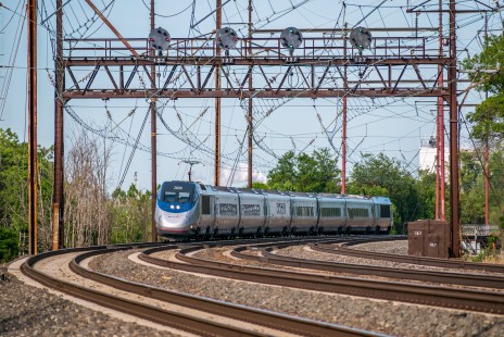 Amtrak Acela train 2154 hustles north through Eddystone, Pennsylvania, during the resumption of limited Acela service, on June 1, 2020.

Robert Sartain of Wallingford, Pennsylvania spent some of his Covid lockdown photographing Amtrak’s Northeast Corridor. In response to the virus, Amtrak cut service dramatically, starting with the cessation of non-stop New York-Washington service on March 10th, and then all Acela service on March 23rd. “As rail photographers, we often hear the adage, ‘shoot the ordinary, for tomorrow it will be gone.’ Sometimes the converse is true, too: sometimes the ordinary is a welcome sight, indeed. On June 1st, Amtrak resumed a limited schedule of Acela service between Washington and New York City. The first Acela northbound that morning was train 2154. In the olden days, i.e., before the month of March, I’d often pass 2154 on my morning commute driving to work. Who knew that three months later that I’d be working remotely from home, but happily would go out of my way to shoot an ordinary Acela resuming her trek northward to New York City, under iconic PRR signals?”

To see additional member work made during the Covid-19 pandemic, see “Creativity & Covid” in the <a href="http://www.railphoto-art.org/railroad-heritage-62/" rel="noreferrer nofollow">Fall 2020 issue of <i>Railroad Heritage</i></a>.