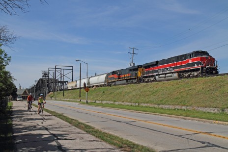 Two bicyclists pass by as Iowa Interstate train SASI (South Amana, Iowa – Silvis, Illionis) rolls off the Government Bridge onto Arsenal Island in Rock Island, Illinois. Leading this June 6, 2020 afternoon is ES44AC 513, painted as a tribute to the late Chicago, Rock Island & Pacific Railroad that once operated where this train is seen.

Brian Carlson, of Rolling Meadows, Illinois, writes that the “unprecedented pause” of 2020 has allowed him to work from home, slow down, and consider his future. “With the arrival of warmer weather, I was feeling the itch to get out and made three photographic expeditions within a few hours’ drive from home.  While I haven’t been able to go on any multi-day, multi-state travel extravaganzas in 2020, this welcomed pause has given me the ability to get caught up on nearly everything else…and the time to ponder where I want to go and what I want to see next.”

To see additional member work made during the Covid-19 pandemic, see “Creativity & Covid” in the <a href="http://www.railphoto-art.org/railroad-heritage-62/" rel="noreferrer nofollow">Fall 2020 issue of <i>Railroad Heritage</i></a>.