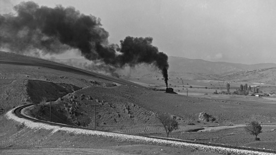 Wind-blown smoke marks the path of a Turkish State Railways freight train steaming south on the Zonguldak Line near Eskipazar, Turkey, on September 17, 1973. Photograph by Victor Hand, Collection of the Center for Railroad Photography & Art, Hand-TCDD-25-194