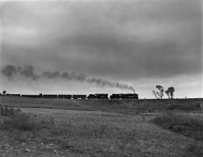 Two Turkish State Railways steam locomotives pull an ore train north under brooding skies on the Samsun-Sivas Line near Dekdigin, Turkey, on September 9, 1973. Czech-built 2-10-0 56159 leads Belgian 2-8-0 45020. Photograph by Victor Hand, collection of the Center for Railroad Photography & Art, Hand-TCDD-25-034