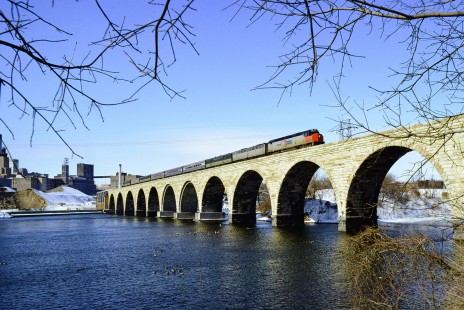 Amtrak's <i>North Coast Hiawatha</i> crosses the Stone Arch Bridge over the Mississippi River in Minneapolis, Minnesota, on March 1, 1975. The last passenger train crossed the bridge in 1978, and the iconic structure is now part of a recreational trail. Photograph by John Gruber, collection of the Center for Railroad Photography & Art, Gruber-07S-02-04