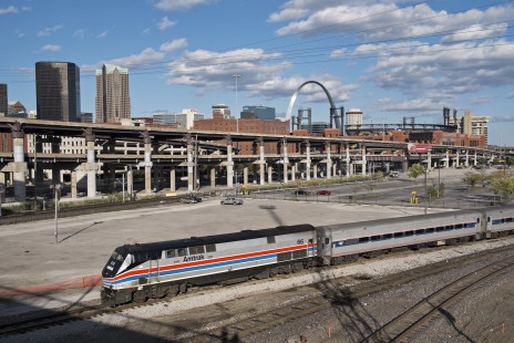 Amtrak locomotive 66 leads the <i>Missouri River Runner</i> in St. Louis on October 4, 2014. Busch Stadium and the Gateway Arch stand in the background behind the elevated lanes of I-64. The locomotive is one of four specially-painted "heritage units" for Amtrak's fortieth anniversary in 2011. Photograph by Scott Lothes, president and executive director of the Center for Railroad Photography & Art