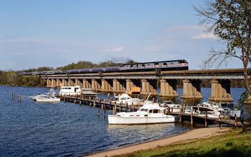 The <i>Auto Train</i> crosses Aquia Creek behind three P30CH locomotives shortly after departing Lorton, Virginia, for its overnight run to Sanford, Florida, on April 16, 1988. The train carries passengers as well as their vehicles between its two terminals, located near Washington and Orlando, respectively. Photograph by Ronald C. Hill, collection of the Center for Railroad Photography & Art, Hill-20-22-32