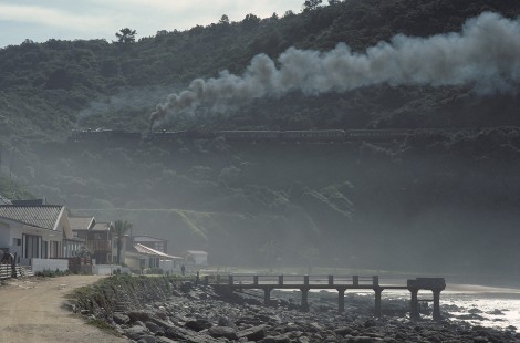 South African Railways 24-class steam locomotive nos. 3684 and 3683 lead westbound passenger train at Victoria Bay in Cape Province (present-day Western Cape), South Africa, on July 23, 1990. Photograph by Katherine Botkin. BOTKINK-113-KT-295, © 1990, Katherine Botkin.