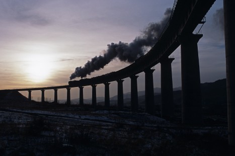Jitong Railway QJ-class steam locomotive nos. 6986 and 7030 lead eastbound freight train over the Simingyi Viaduct, west of Hadashan, Inner Mongonlia, China on December 4, 2008. Photograph by Katherine Botkin. BOTKINK-103-KT-204, © 2008, Katherine Botkin