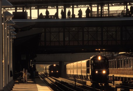 Two westbound MTA trains pull into Woodside Station in New York City on November 5, 1998.

Judges' comments: Waiting passengers, platforms, and trains encapsulate the story of this winning submission. Intrigued by the photographer’s use of time of day and season juxtaposed across a theater of personalities waiting for the next train, the judges noted this series delivers a fascinating story of urban commuting. The winter scene of bundled passengers looking toward an arriving predawn train to New York City chills the senses, while the foggy summer Chicago sunrise at the Roosevelt CTA Station reminds the viewer how just a silhouette and pose can speak volumes about people without ever showing their facial expressions. The third, autumn image reminds the viewer that multi-modal, bi-level transfer platforms offer yet again another unique image-making opportunity. 

Read more about the 2021 John E. Gruber Creative Awards Program: <a href="https://railphoto-art.org/awards/2021-awards/" rel="noreferrer nofollow">railphoto-art.org/awards/2021-awards/</a>