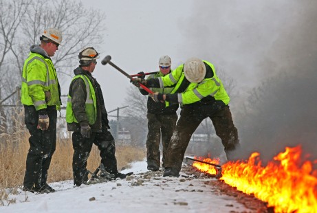 CN's Dubuque Subdivision came apart during an overnight run in frigid temperatures on January 10, 2016; section crews spent forty-eight hours chasing down broken rails. At mile 269.9, just west of Raymond, Iowa, a crew member swings a sledge hammer to hit the heated rail back into place. 

Judges' comments: A broken rail in winter visually narrates the constant battle with nature that the men and women who maintain railroads must endure. The photographer deftly presents the track crew as they heat and align adjacent sections of rail. Hydraulic jacks, sledge hammers, sweat, snow, and flames all shape this memorable series.

Read more about the 2021 John E. Gruber Creative Awards Program: <a href="https://railphoto-art.org/awards/2021-awards/" rel="noreferrer nofollow">railphoto-art.org/awards/2021-awards/</a>