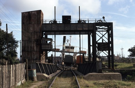 In Buenos Aires, Argentina, the General Urquiza Railroad (Ferrocarril General Urquiza) operated a totally isolated yard of standard gauge track that was fed by a train ferry operation from points up river on the Río de La Plata-Parana River system. On July 6, 1973, the ferry prepares to depart from South Dock (Dársena Sur).

Judges' comments: These three rail ferry images immediately captivated the judges for their evocative composition and Kodachrome color vitality. They magically transport the viewer on an exotic visual journey that parallels that of the railcar’s physical transfer from land to water. Each image offers a portal to an earlier age, rendered in soft colors and compositions that evoke movement. 

Read more about the 2021 John E. Gruber Creative Awards Program: <a href="https://railphoto-art.org/awards/2021-awards/" rel="noreferrer nofollow">railphoto-art.org/awards/2021-awards/</a>