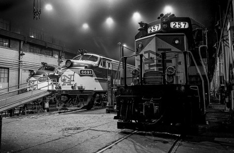 Overhead lighting ﬁxtures glare as three of Shore Line East’s ﬂeet of New Haven-painted locomotives rest for the evening in New Haven, Connecticut, on June 19, 1992.

Judges' comments: The photographer invites the viewer to approach, enter, and almost touch the subject in this series of night images of a New Haven Railroad engine house. The bold, simple use of tones and composition punctuates and defines the shed’s spatial threshold in the first image, as well as the silhouetted form of the locomotive in the second. In the third, close-up image, the photographer deftly distilled the composition to the bare essentials of storytelling. The interior lighting, piercing the grainy, exhaust-filled space above, further captivated the judges to select this work for second prize.

Read more about the 2021 John E. Gruber Creative Awards Program: <a href="https://railphoto-art.org/awards/2021-awards/" rel="noreferrer nofollow">railphoto-art.org/awards/2021-awards/</a>