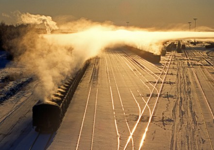 A temperature inversion traps rising steam from freshly backed taconite pellets at DM&IR’s Proctor, Minnesota, yard on December 2, 2000.  

Judges’ Comments: A fascinating composition, with strong formal elements shrouded in steaming taconite filled railcars backlit by brilliant sunshine, combine to form this remarkable image. 

Read more about the 2022 John E. Gruber Creative Photography Awards: <a href="https://railphoto-art.org/awards-2022/" rel="noreferrer nofollow">railphoto-art.org/awards-2022/</a>